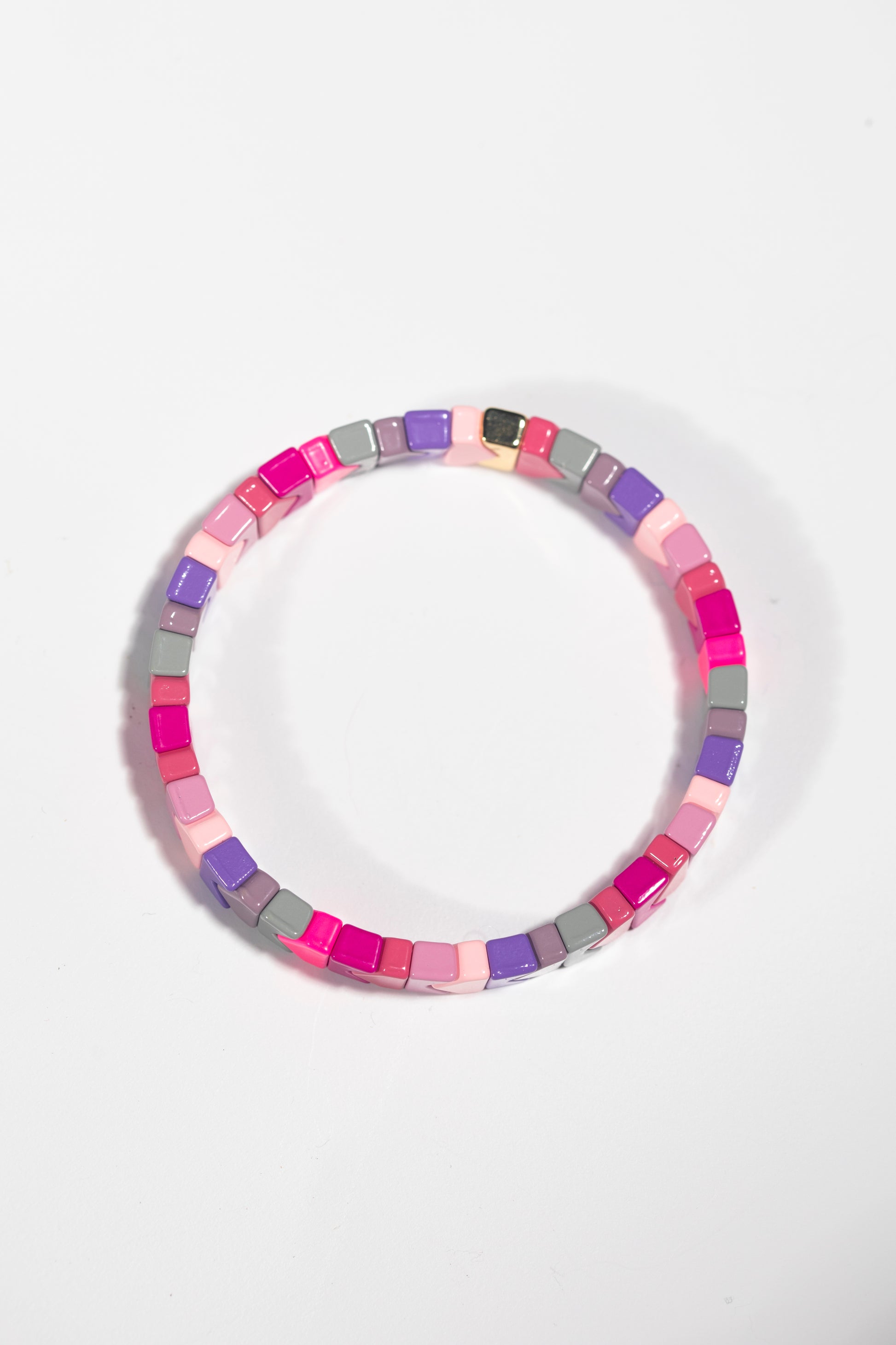 An elastic tile bracelet photographed straight-on against a white background. The bracelet is made of square tiles in a pastel and bright color palette including hot pink, light pink, purple, grey, and mauve. The tiles are arranged in a seamless circle, creating a cohesive pattern.