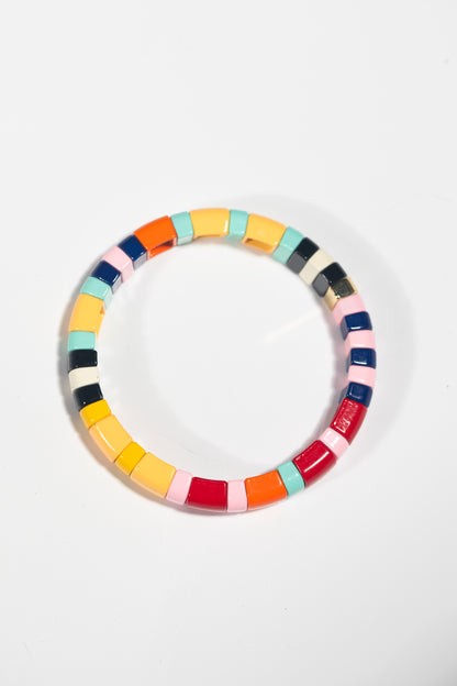 A single tile bracelet photographed from above on a white background. The bracelet forms a perfect circle and is made up of rectangular tiles in a mix of colors including yellow, red, navy blue, mint green, pink, orange, and black. Each tile has a glossy finish that catches the light.