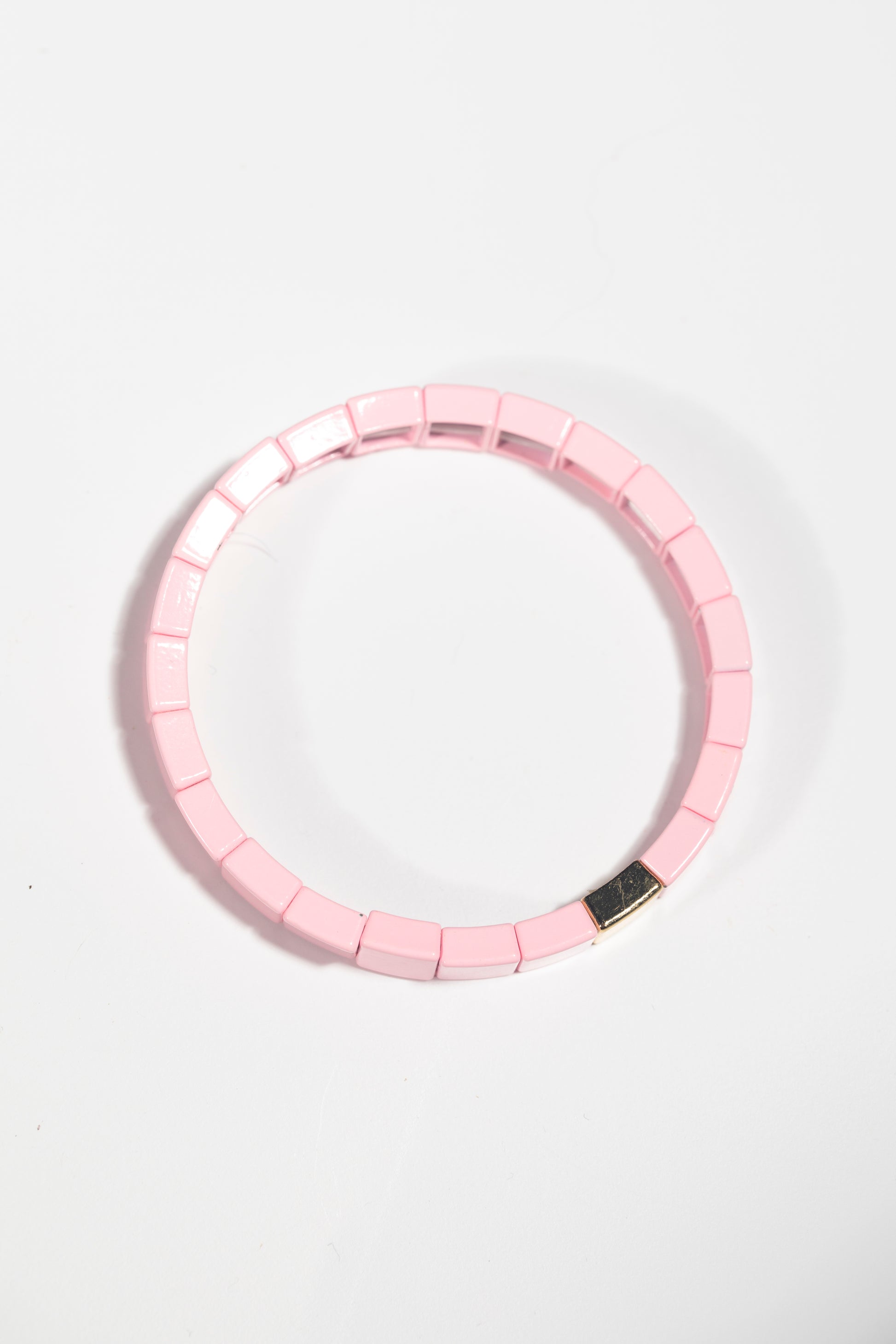 Pastel pink enamel bracelet with square tiles and gold accent on white background