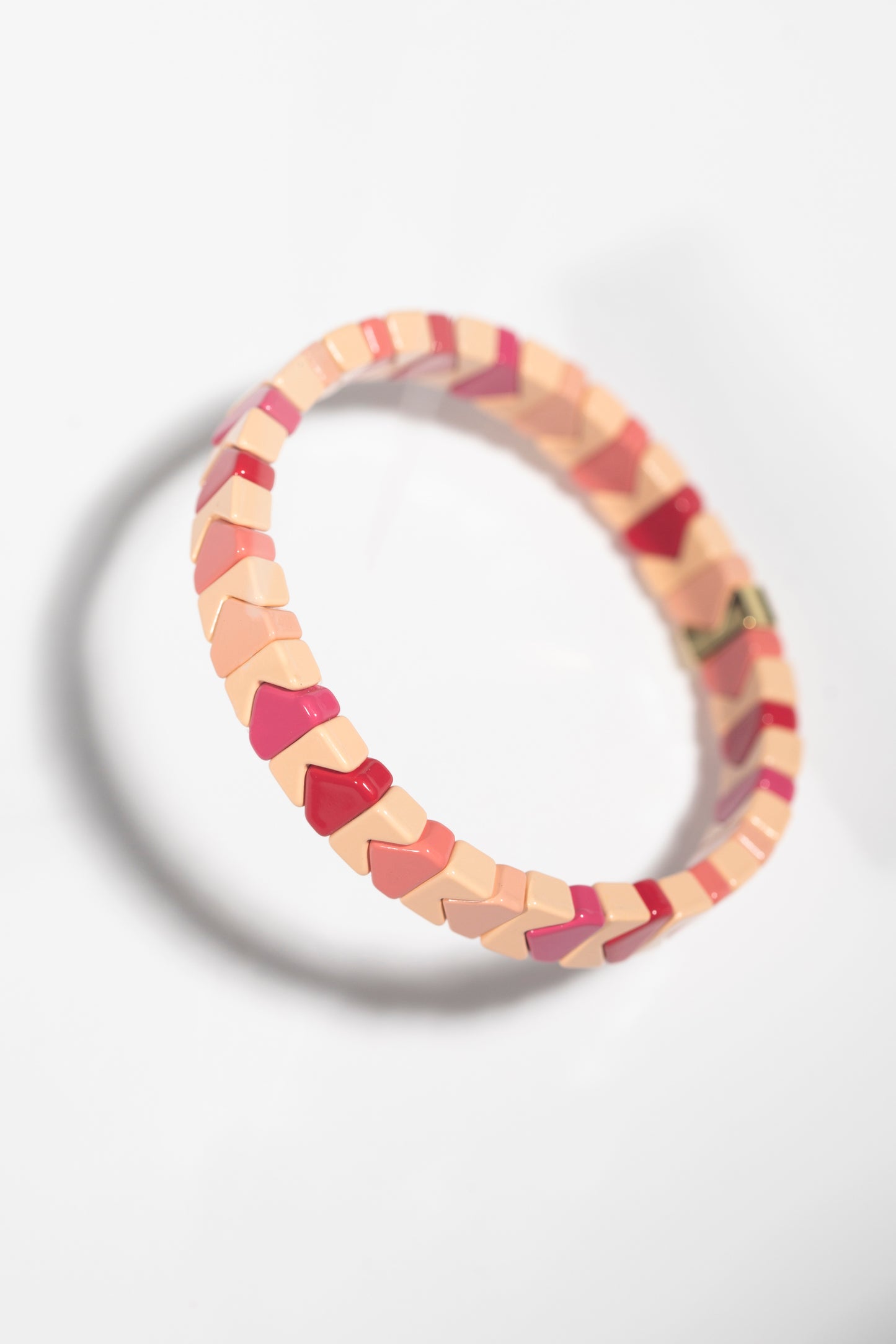 Cream and burgundy bracelet with chevron-shaped tiles photographed at angle, creating shadow