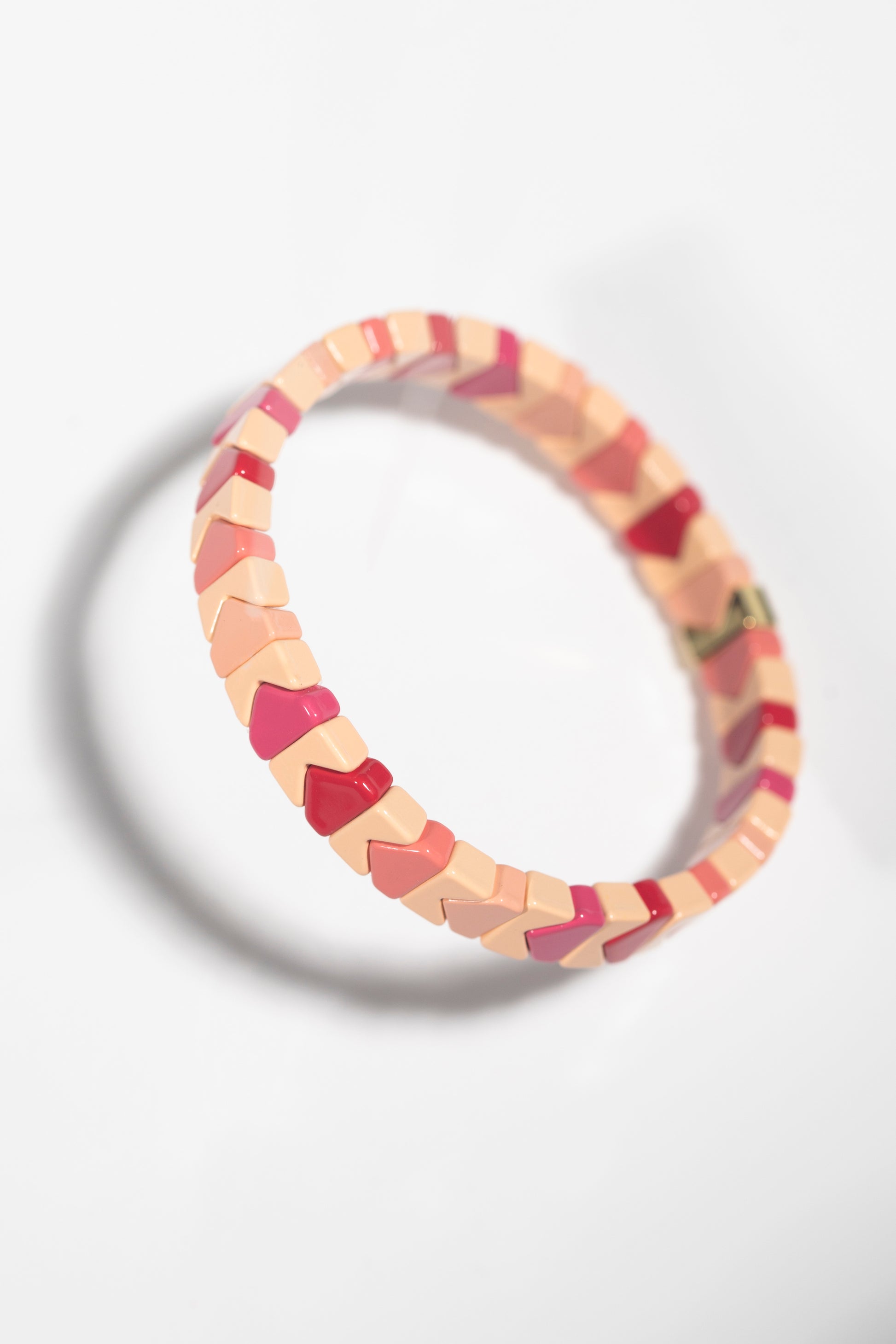 Cream and burgundy bracelet with chevron-shaped tiles photographed at angle, creating shadow